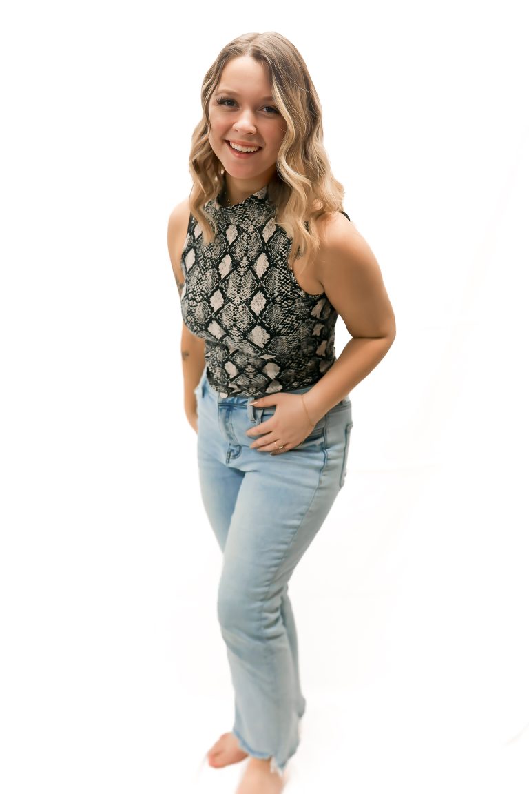 Smiling person in snakeskin top and jeans.